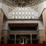 Mosque interior with stone walls, arched windows and a red carpet