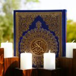 Blue Quran with gold calligraphy and white candles