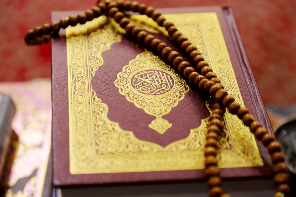 An ornate Quran with wooden prayer beads, symbolizing faith and devotion in Islam.